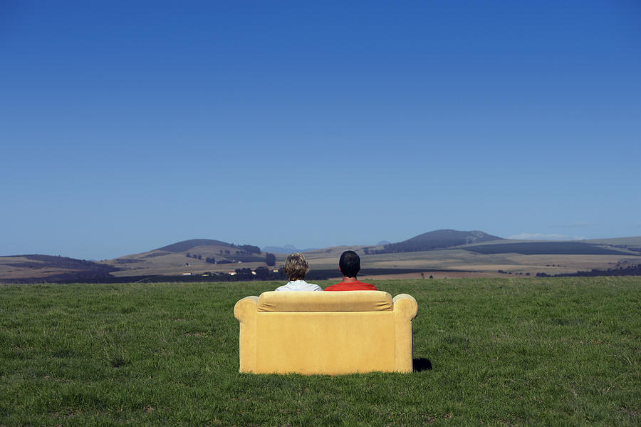 Rear View of a Couple Sitting on a Sofa and Looking at the View of Open Countryside Photograph by Digital Vision.