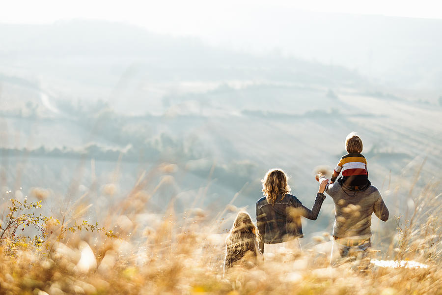 Rear view of a family standing on a hill in autumn day. Photograph by Skynesher