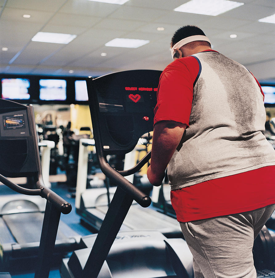 Rear View of a Man Walking on a Running Machine Photograph by Digital Vision.