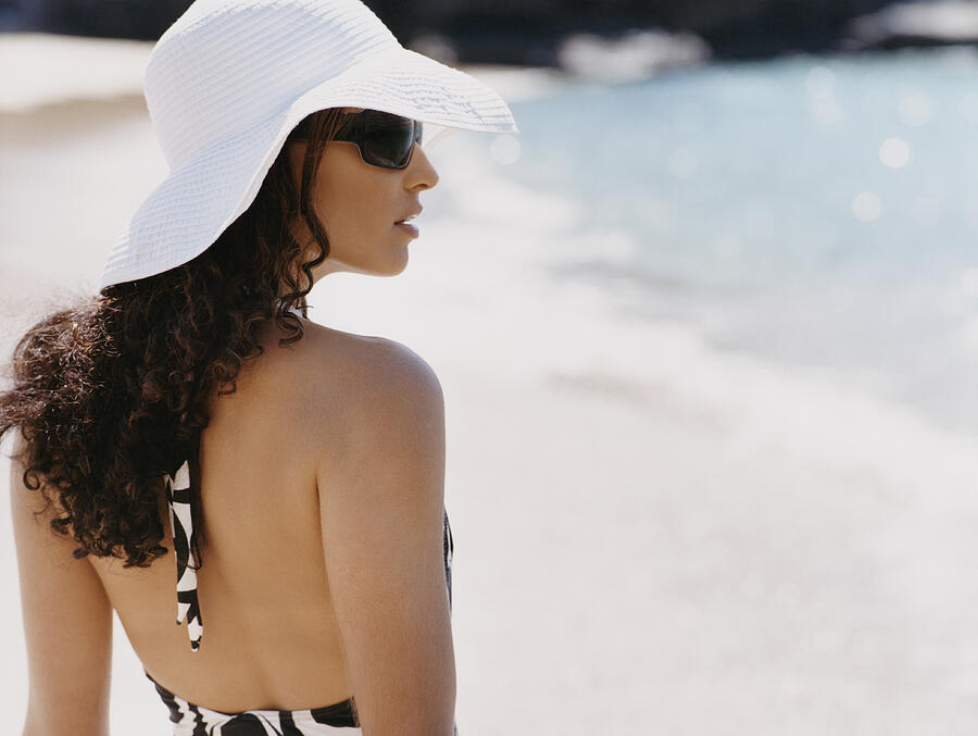 Rear View of a Woman in a Sunhat and Sunglasses Standing on the Beach Photograph by Digital Vision.