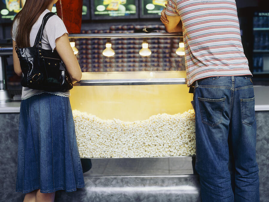 Rear view of a young couple near a popcorn machine Photograph by Stockbyte