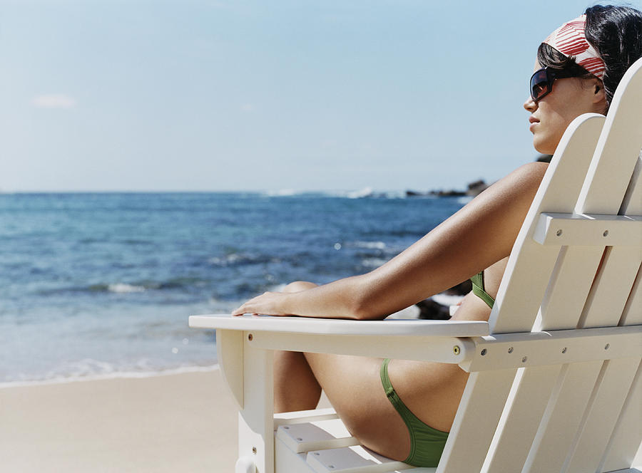 Rear View of a Young Woman in a Bikini Sitting on a Sunlounger on the Beach Photograph by Digital Vision.
