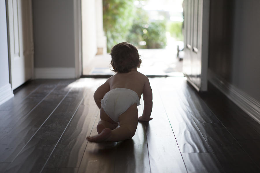 Rear view of baby boy wearing nappy crawling towards open front door Photograph by Raphye Alexius