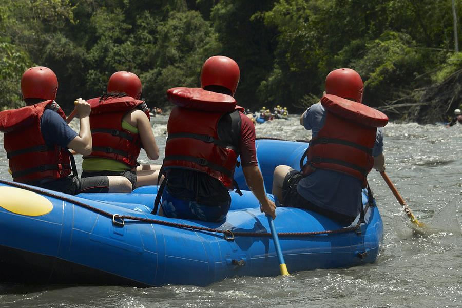 Rear view of four people rafting in a river Photograph by Glowimages