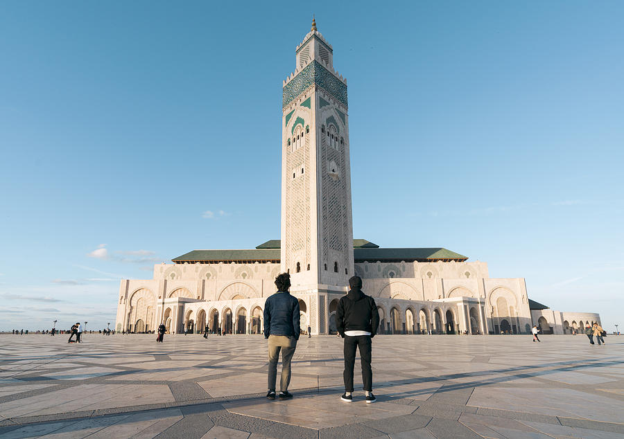 Rear view of friends standing against Mosque Hassan II Photograph by Cavan Images