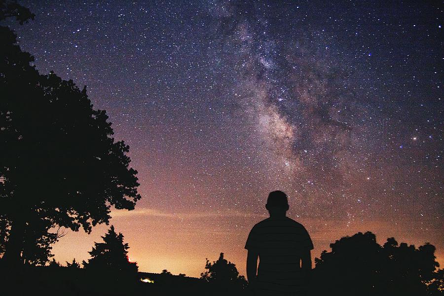 Rear View Of Man Standing By Silhouette Trees Against Star Field In Sky Photograph by Josue Enriquez / EyeEm