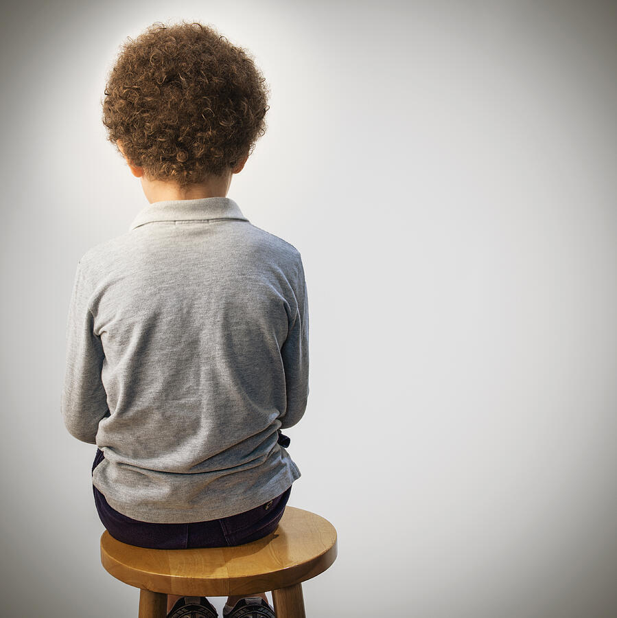 Rear view of mixed race boy sitting on stool Photograph by Jose Luis Pelaez Inc