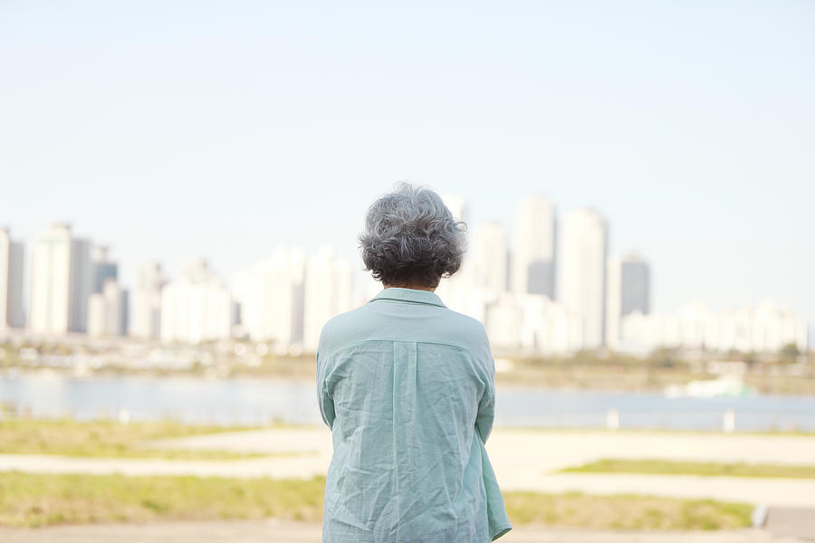 Rear view of senior woman standing by river bank Photograph by Runstudio