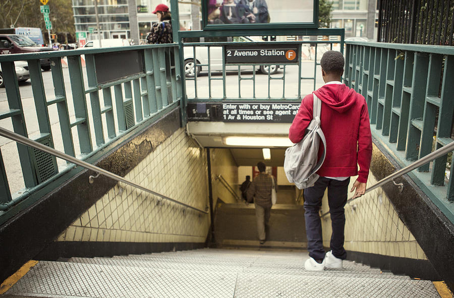 Rear view of student walking down steps in subway Photograph by Cavan Images