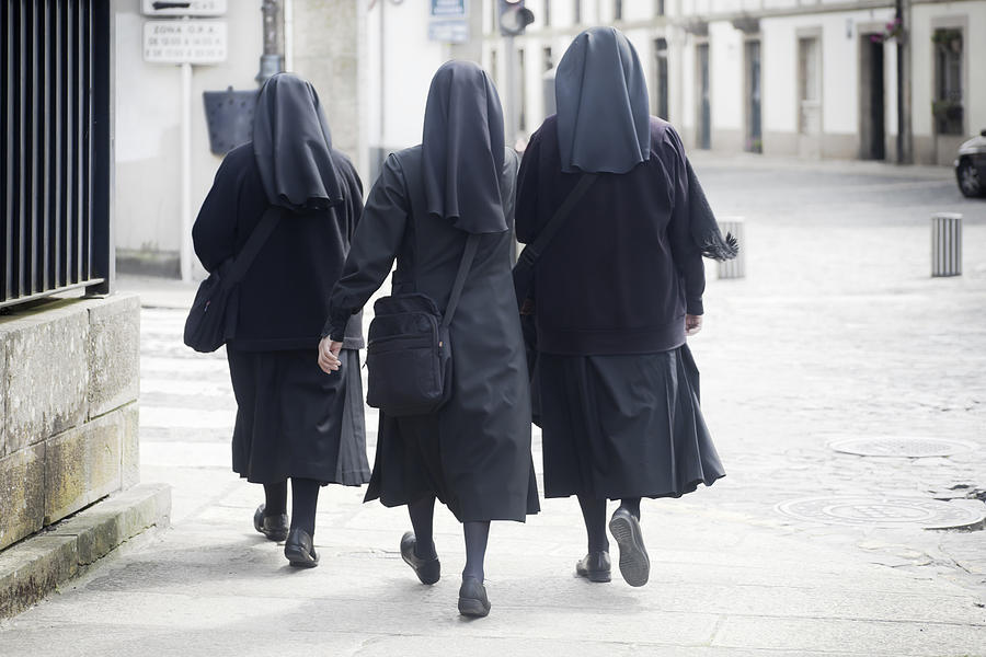 Rear view of three nuns walking in the street. Photograph by Percds