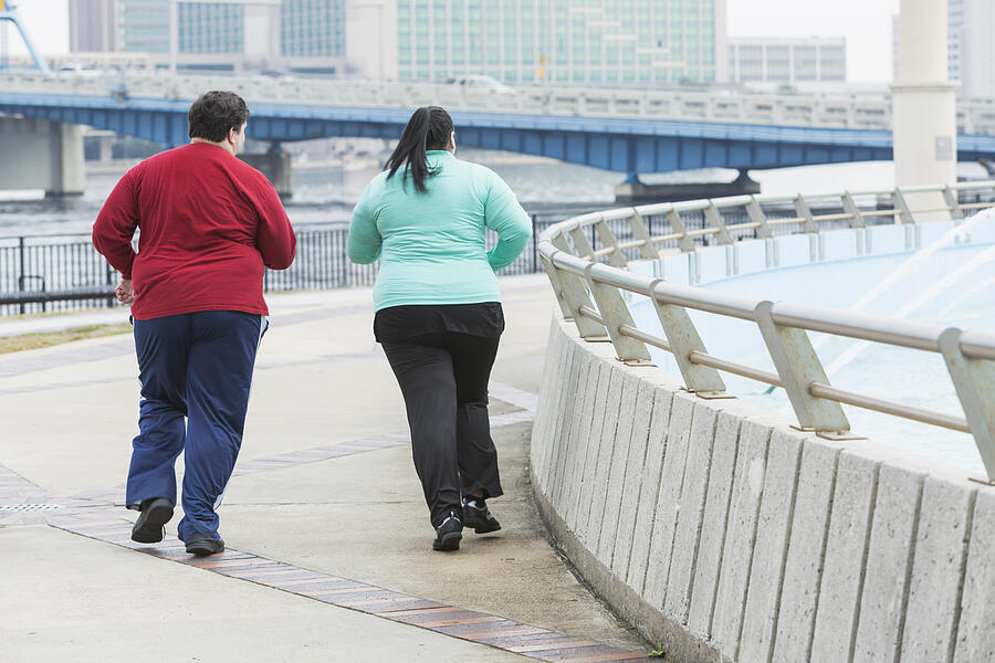 Rear view of two overweight people jogging Photograph by Kali9