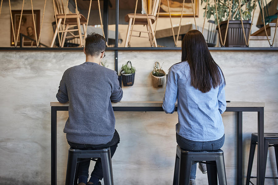 Rear view of young woman and man sitting in a cafe Photograph by Westend61