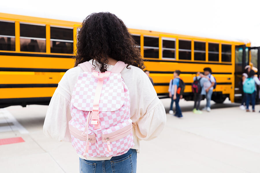 Rear view preteen girl with back pack walking toward bus Photograph by SDI Productions
