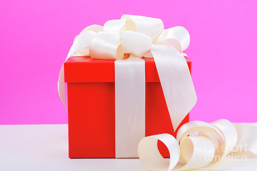 Red and white gift on pink background.  Photograph by Milleflore Images