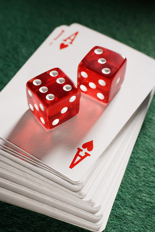 Red dice on pile of playing cards, close-up Photograph by Nicholas Rigg
