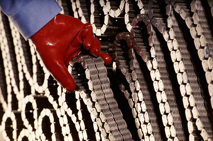Red Gloved Hand Removing a Coiled Chain Photograph by Digital Vision.