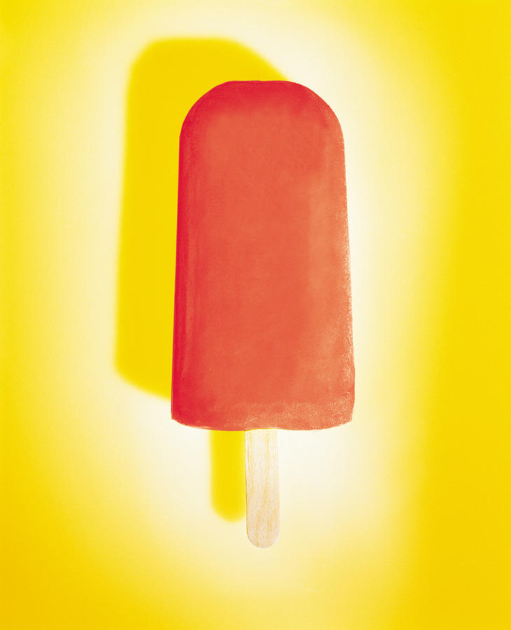 Red ice pop on yellow background Photograph by Photodisc