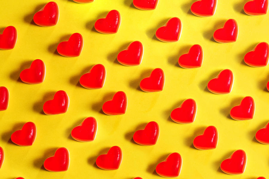 Red jelly heart shaped sweets on a yellow background Photograph by Emilija Manevska