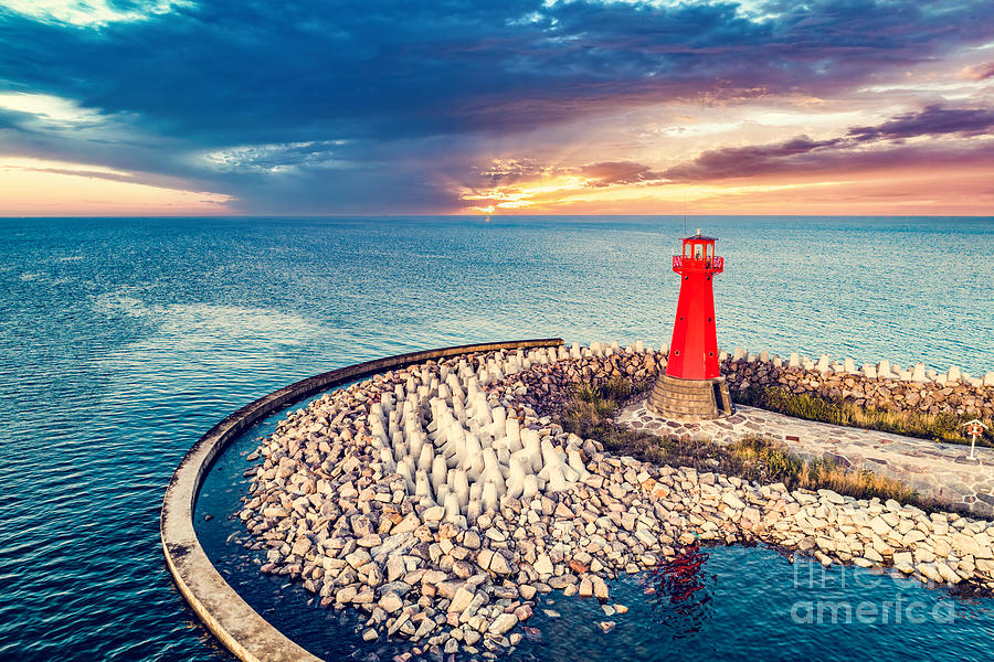 Red lighthouse on rocky harbor at sunset Photograph by Michal Bednarek