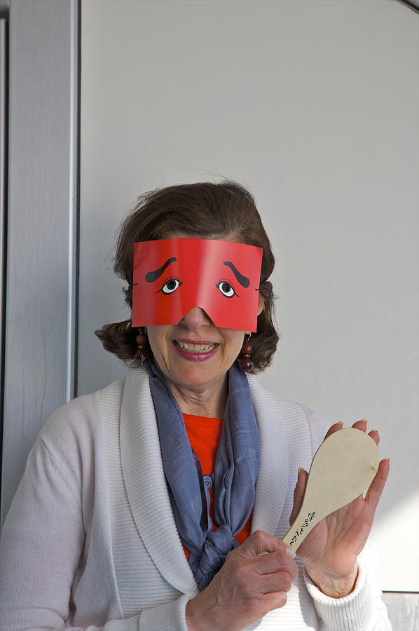 Red paper cut-out mask on smiling woman Photograph by Barry Winiker
