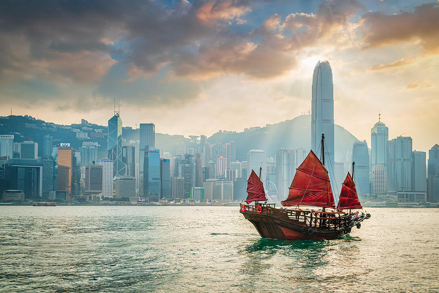 Red Sail Junkboat Cruising Along Hong Kong Cityscape at Sunset Photograph by Mlenny