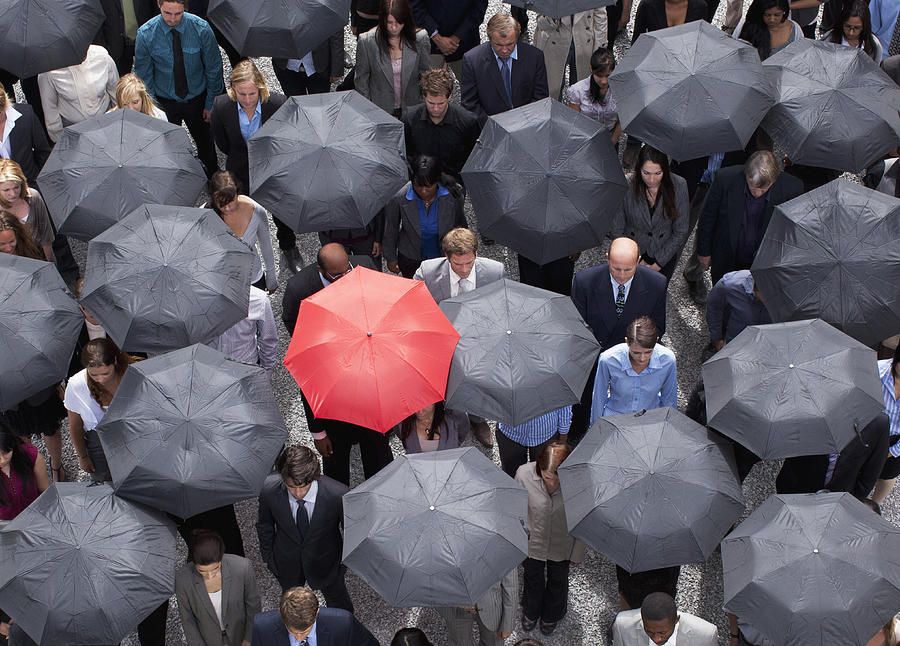 Red umbrella standing out in crowd of business people Photograph by Martin Barraud