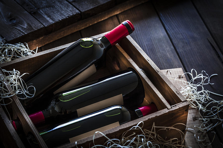 Red wine bottles packed in a wooden box shot rustic wooden table Photograph by Fcafotodigital