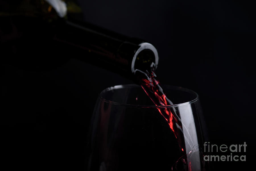 Red Wine Pouring In Wine Glass Over Black Background. Closeup Of Photograph