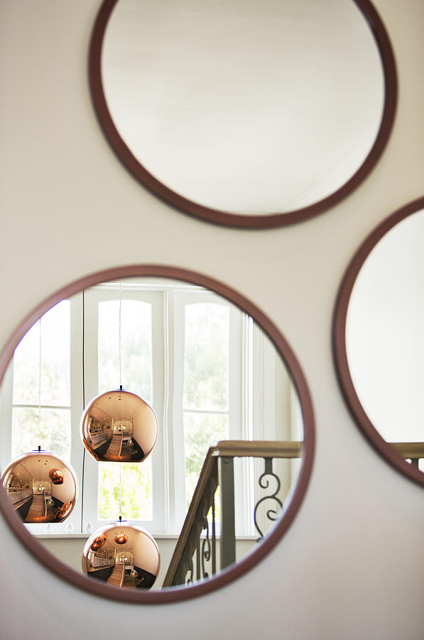 Reflection of copper pendant lights in round mirror Photograph by Hoxton/Tom Merton