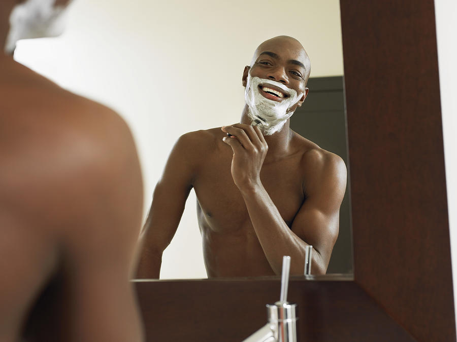 Reflection of Man Shaving in a Bathroom Mirror Photograph by Digital Vision.
