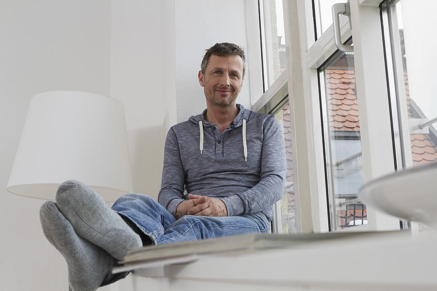 Relaxed man sitting on windowsill Photograph by Westend61