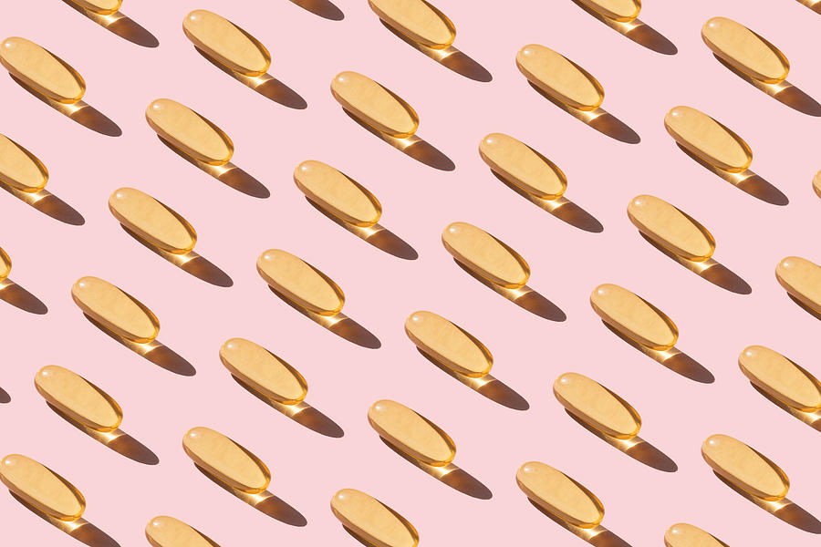 Repeated fish oil pills on pink background Photograph by Yulia Reznikov