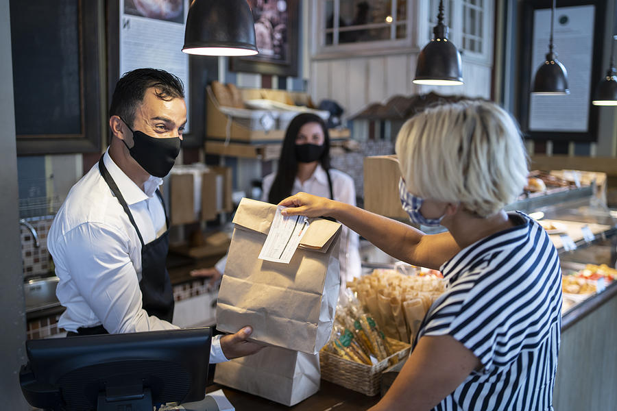 Restaurant employers giving packed food away to a customer. Reopening after COVID-19 quarantine concepts. Photograph by Vladimir Vladimirov