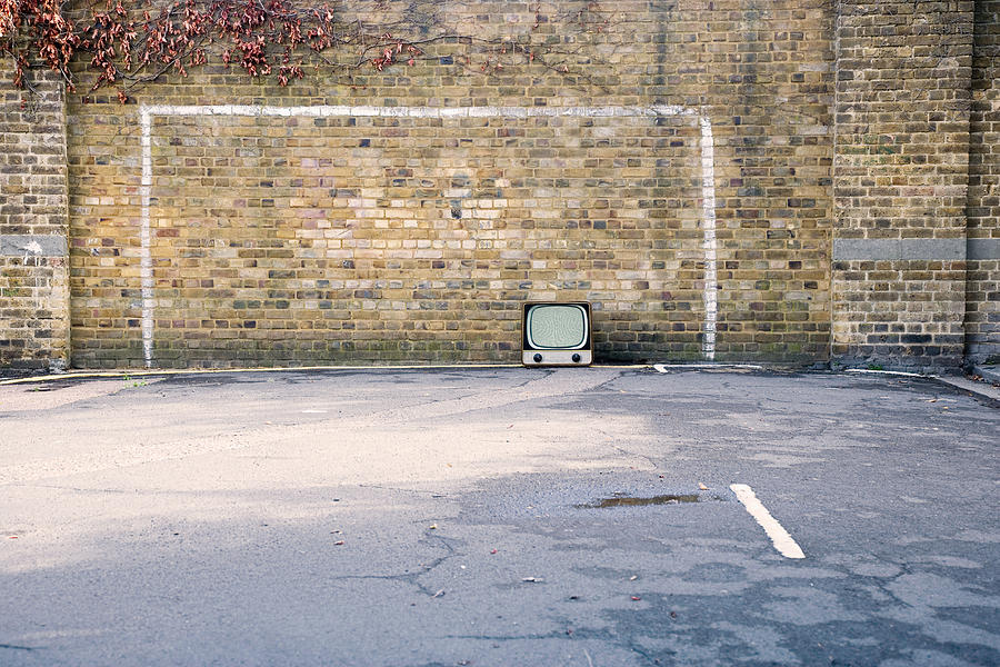 Retro television in football goal painted on brick wall Photograph by Cultura/Neil Guegan
