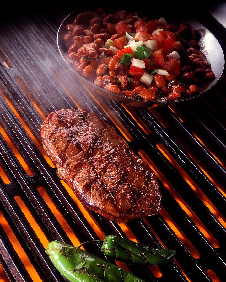 Rib eye steak on grill with beans Photograph by Jupiterimages