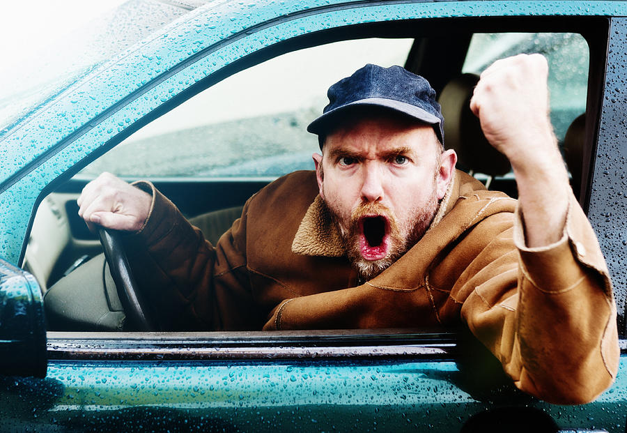 Road rage: Furious male driver yelling, shaking fist through window Photograph by RapidEye