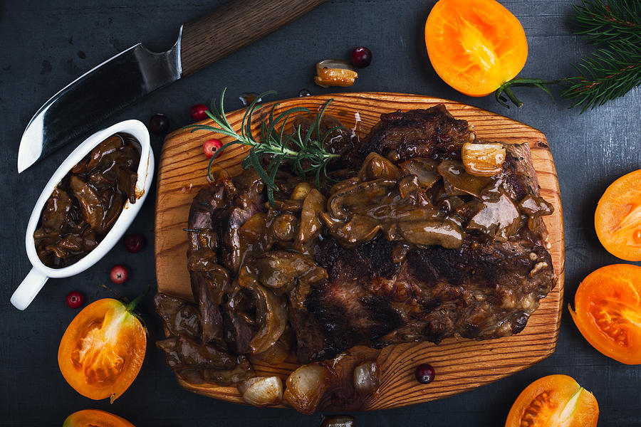Roasted veal steak on board served with mushroom sauce viewed from above, Christmas dinner Photograph by Istetiana