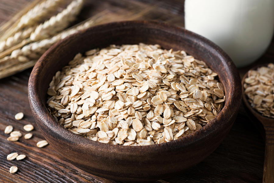 Rolled oats in wooden bowl on old wooden table Photograph by Arx0nt