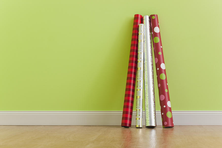 Rolls of Christmas wrapping paper leaning against wall Photograph by Vstock LLC