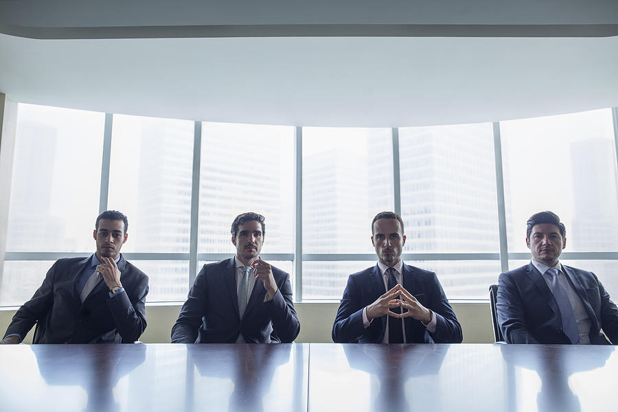 Row of businessmen sitting at conference table Photograph by Shannon Fagan