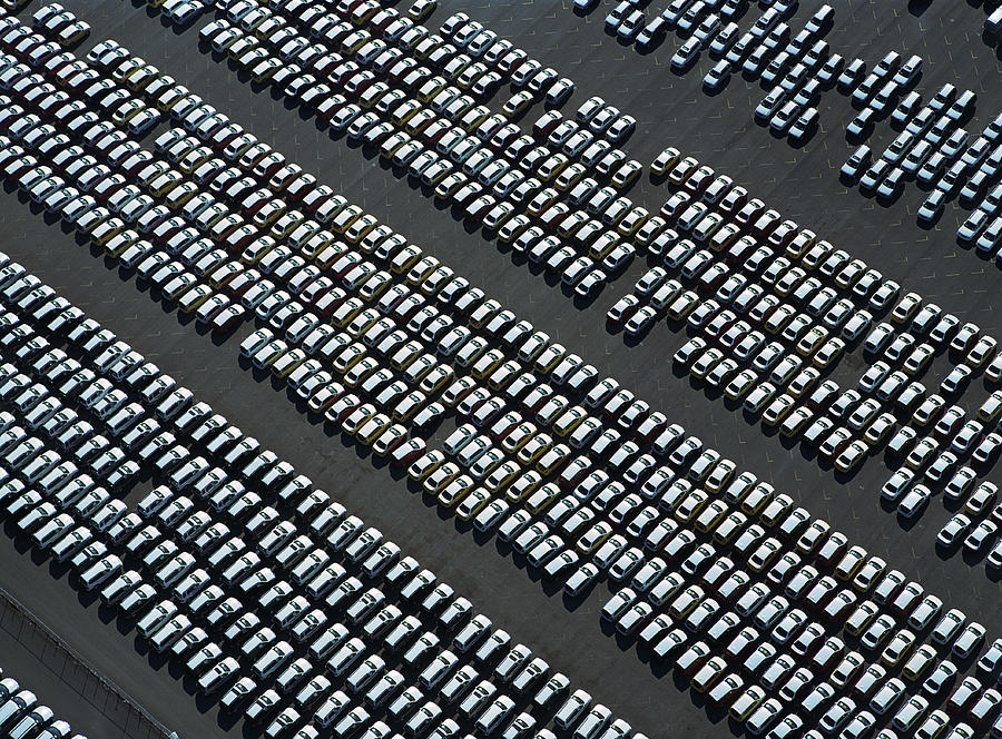 Rows of new cars parked in parking lot, aerial view Photograph by Ryan McVay