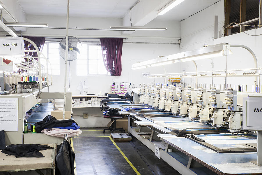 Rows of programmed embroidery machines speed stitching cloth in clothing factory Photograph by Luka Storm