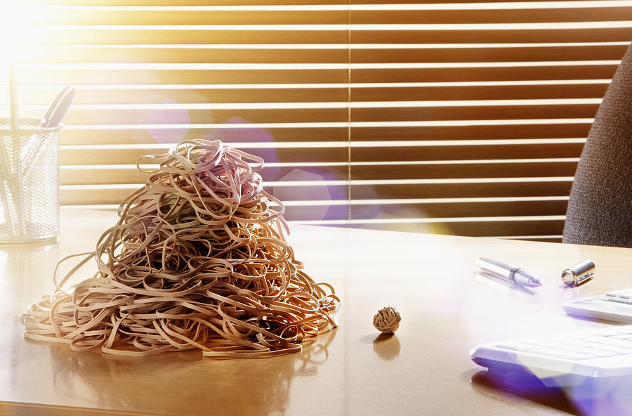 Rubber band ball next to pile of bands. Photograph by Robert Decelis