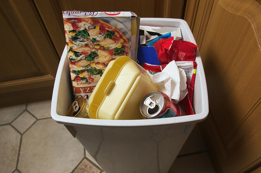 Rubbish bin filled with empty food packaging, close-up Photograph by GSO Images