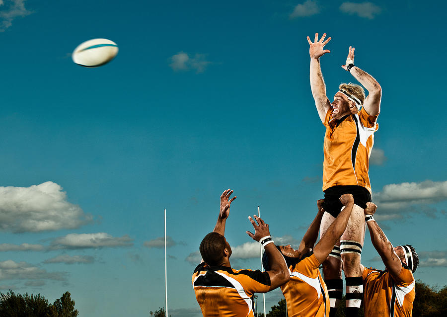 Rugby player leaping up to catch ball Photograph by Rivers Dale