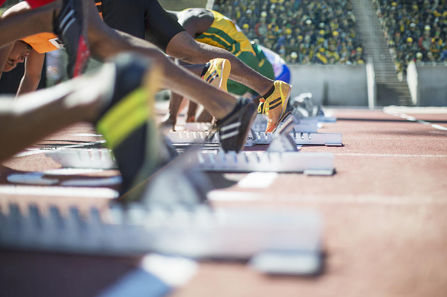 Runners poised at starting blocks on track Photograph by Caia Image