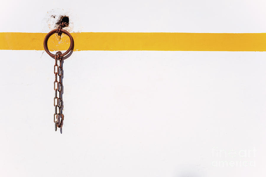 Rural background of a rusty ring on a white wall with orange line to tie animals. Photograph by Joaquin Corbalan