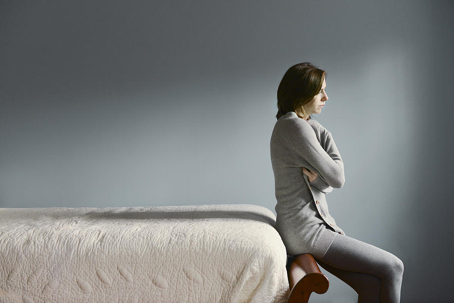 Sad Caucasian woman sitting on bed frame Photograph by Shestock
