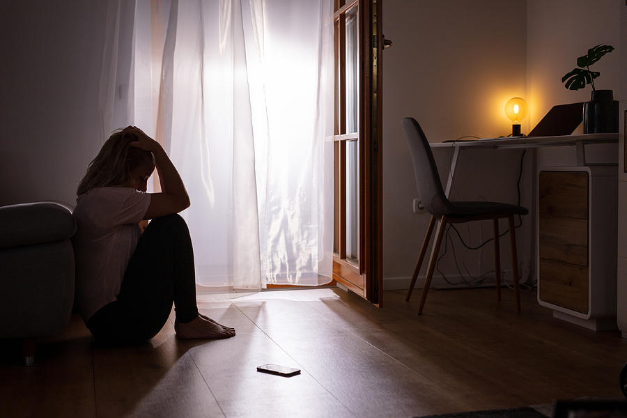 Sad depressed woman crying at home. Dark room. Photograph by SimonSkafar