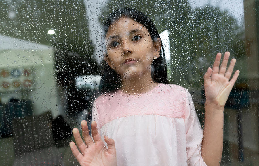 Sad little girl looking out the window on a rainy day looking pensive Photograph by Hispanolistic